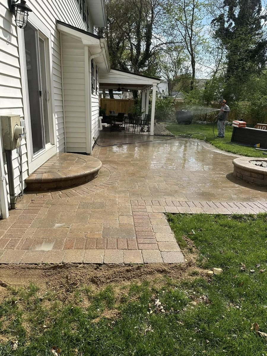 Cleaned pavers still wet, wrapping around the corner of the house toward the covered porch