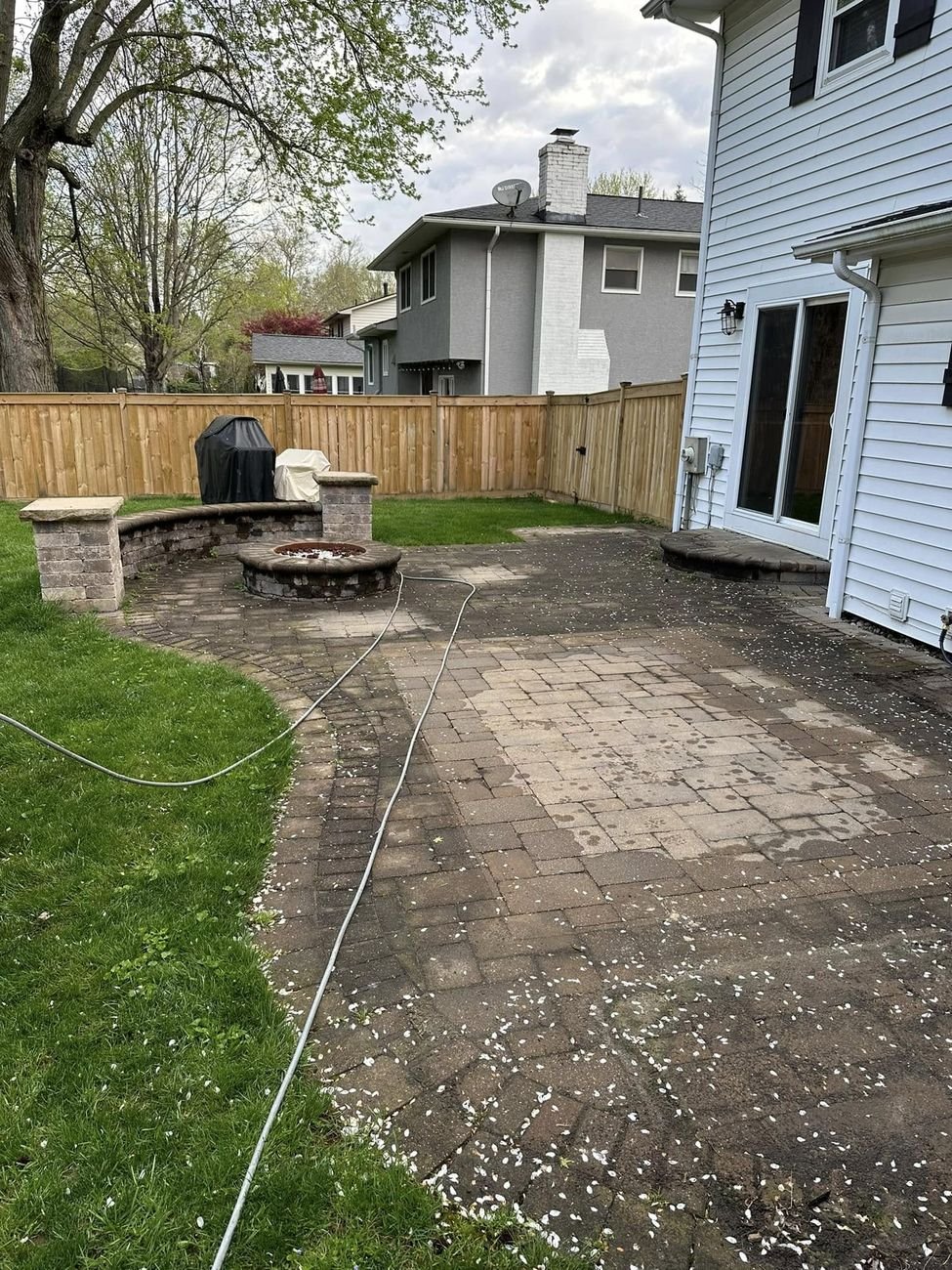 Paver patio gone flat gray with algae and ground in dirt, seat wall and fire pit the same dull color
