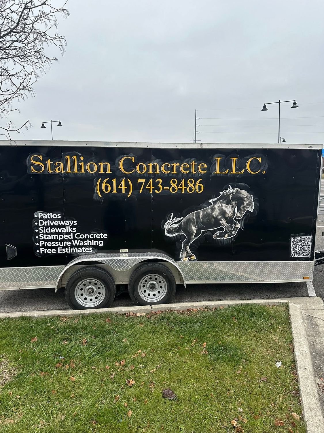 The Stallion Concrete enclosed trailer, black with gold lettering and a rearing horse painted on the side